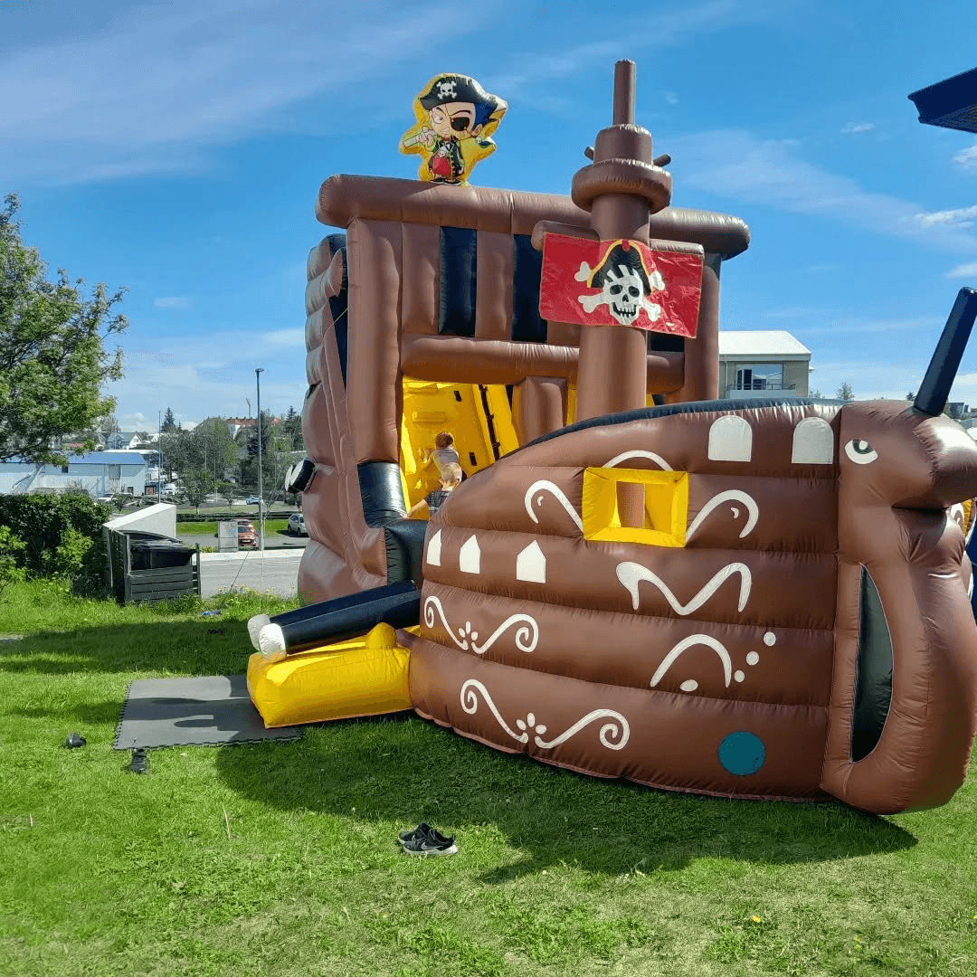 Large inflatable pirate-ship play castle outdoors in summer sun, one of Kastalar – Leiktækjaleiga’s play structures.